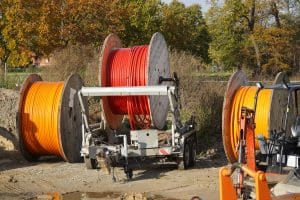Large reels of new fiber optic cable in red and orange, expansion of high-speed Internet in rural regions.