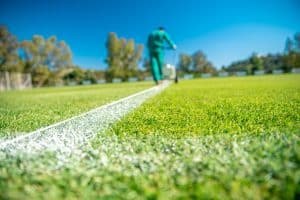 drawn white lines on the football field with white paint on the grass using a special machine before a game.