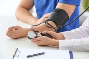 Doctor measuring blood pressure of young man in clinic medical negligence