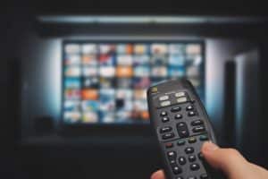 VOD service on television. Man watching TV, streaming service, video on demand, remote control in hand.