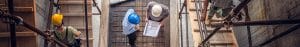 Multiple builders looking at a building plan and walking up and down scaffolding