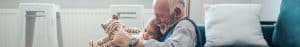 Older man and child smiling and holding a toy